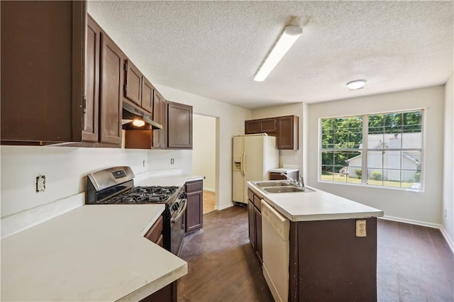 kitchen featuring sink, dark brown cabinets, a textured ceiling, an island with sink, and white appliances