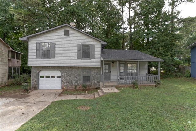 split level home featuring covered porch, a front yard, and a garage