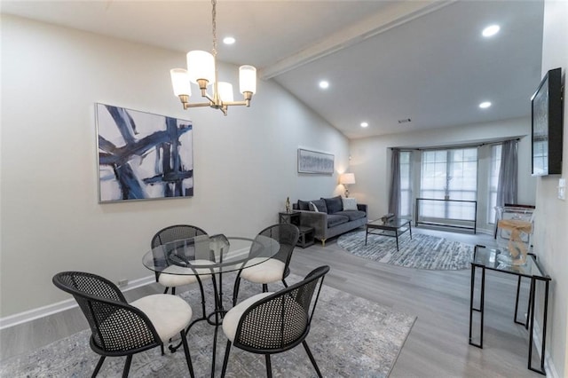 dining area with lofted ceiling with beams, light wood-type flooring, and a notable chandelier