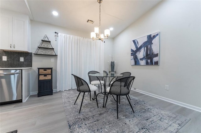 dining area featuring light hardwood / wood-style floors and an inviting chandelier