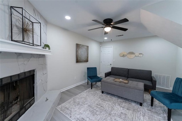 living room with ceiling fan, a fireplace, and light hardwood / wood-style flooring