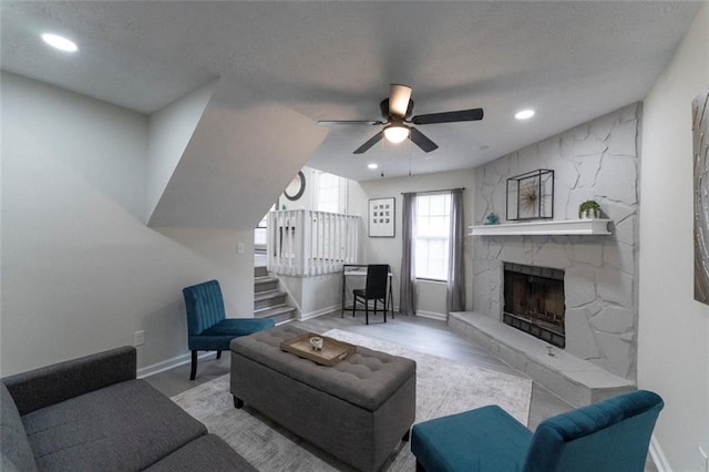 living room featuring ceiling fan, a fireplace, and light hardwood / wood-style flooring