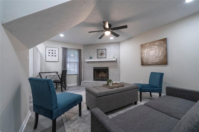 living room featuring a textured ceiling, ceiling fan, and a fireplace