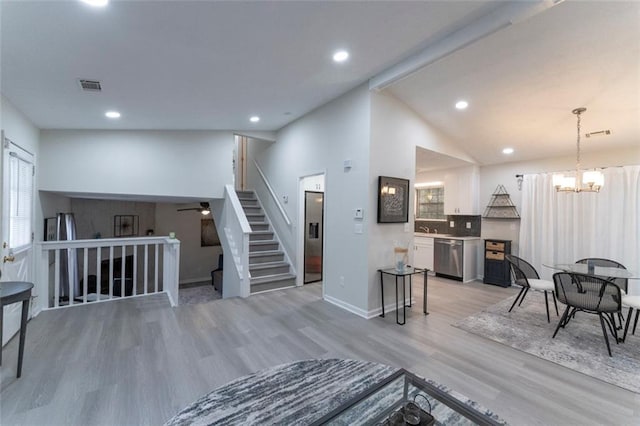 interior space with vaulted ceiling, hardwood / wood-style floors, ceiling fan with notable chandelier, and sink