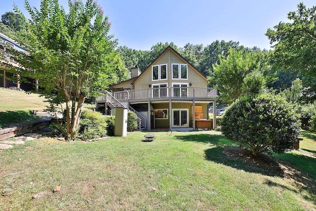 rear view of house featuring a lawn, a wooden deck, and a fire pit