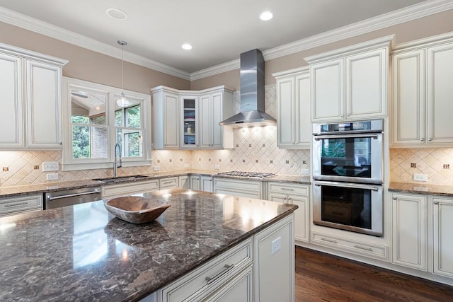 kitchen with dark stone countertops, wall chimney exhaust hood, decorative light fixtures, and stainless steel appliances