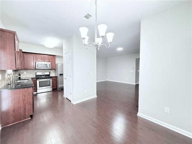 kitchen with stainless steel appliances, a chandelier, decorative backsplash, dark wood finished floors, and hanging light fixtures