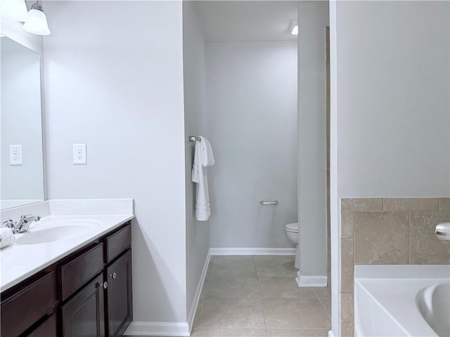 bathroom featuring tile patterned floors, vanity, a bath, baseboards, and toilet