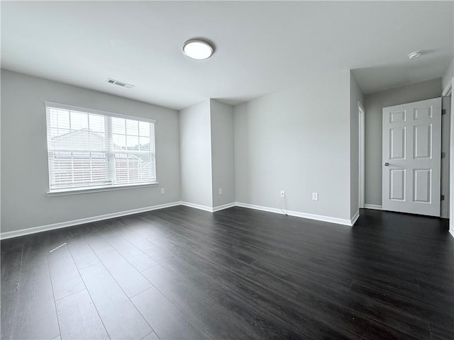 unfurnished room featuring dark wood-style flooring, baseboards, and a smoke detector