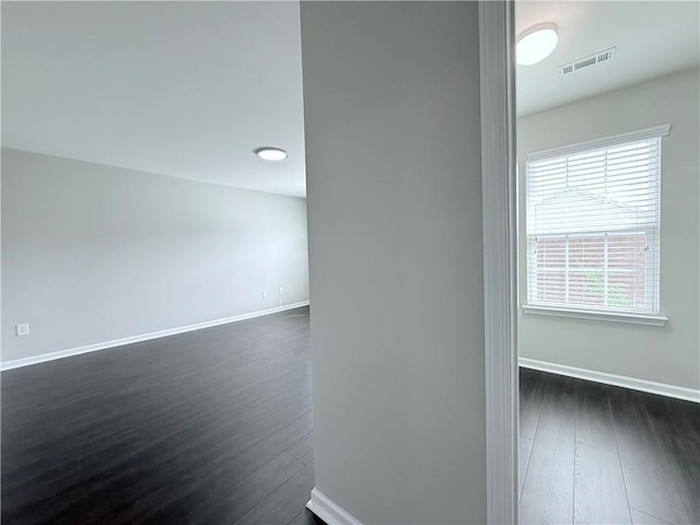 spare room with baseboards, dark wood-type flooring, and healthy amount of natural light