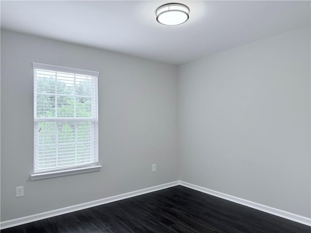 spare room featuring baseboards and dark wood finished floors