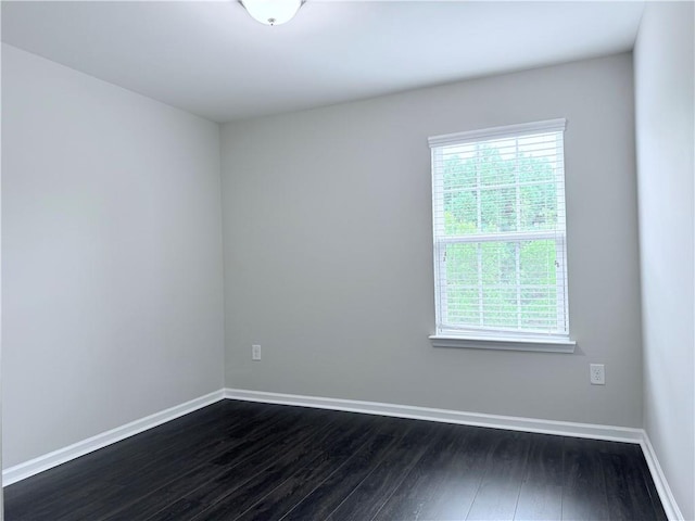 empty room with dark wood finished floors and baseboards