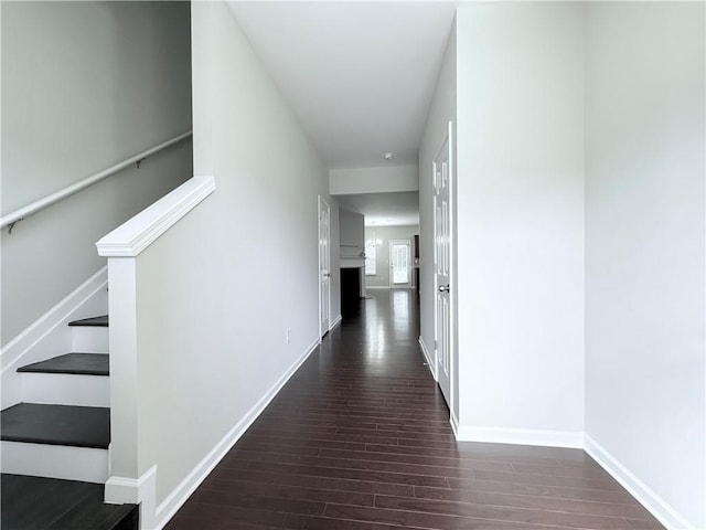 hall with dark wood finished floors, stairway, and baseboards