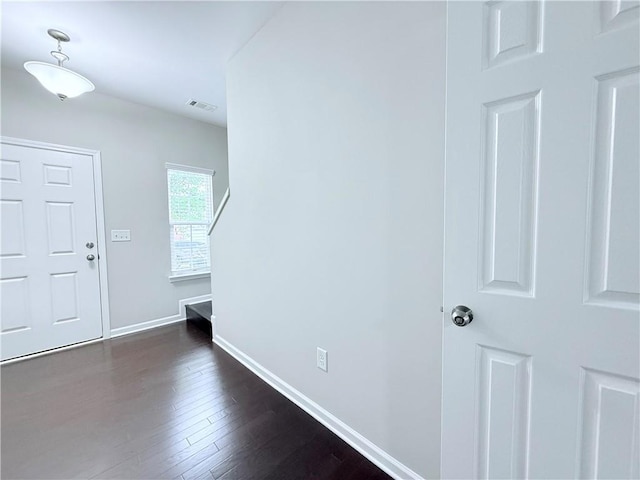 foyer featuring baseboards and dark wood-type flooring