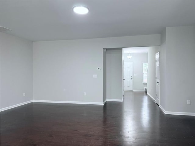 empty room featuring dark wood-style flooring and baseboards