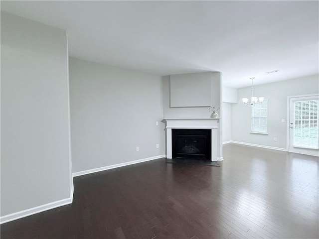 unfurnished living room with a chandelier, dark wood finished floors, baseboards, and a fireplace with flush hearth