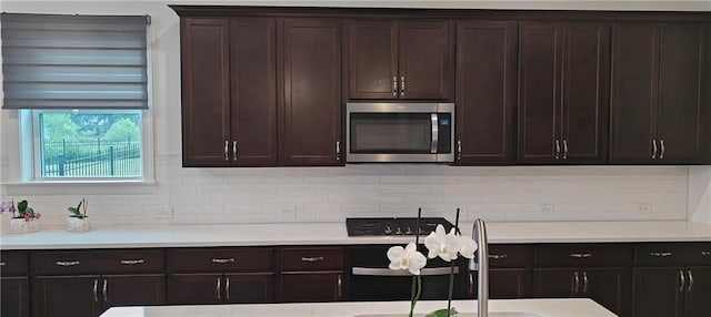 2962 Girard Ln, Duluth, GA 30097 - kitchen with stainless steel microwave, light countertops, tasteful backsplash, and dark brown cabinets
