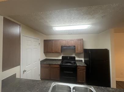 kitchen with a textured ceiling, dark countertops, black appliances, and range hood