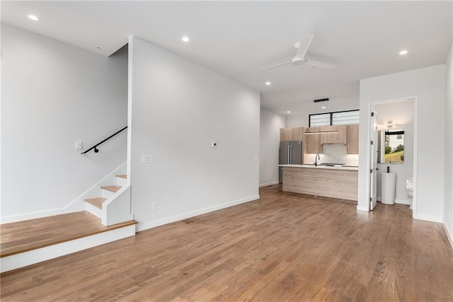 unfurnished living room with sink, ceiling fan, and light hardwood / wood-style floors