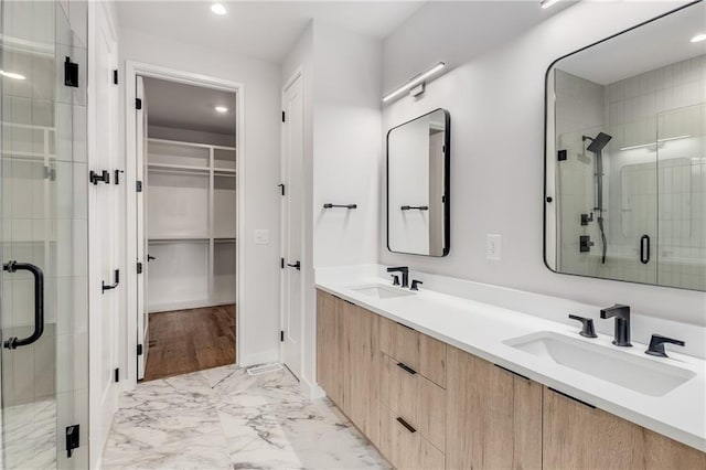 bathroom featuring a shower with shower door and vanity