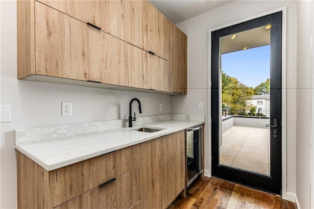 kitchen featuring sink, light brown cabinetry, light stone countertops, wine cooler, and dark wood-type flooring