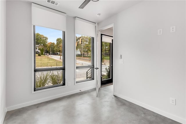 spare room with ceiling fan, concrete flooring, and a wealth of natural light