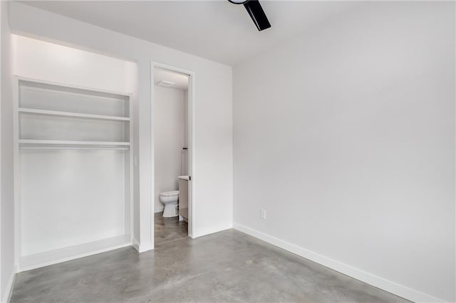 unfurnished bedroom featuring concrete flooring, a closet, ceiling fan, and connected bathroom