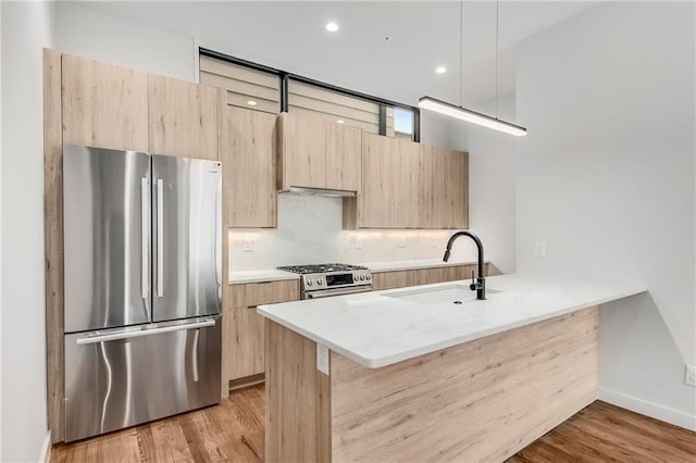 kitchen with light hardwood / wood-style flooring, stainless steel appliances, light brown cabinetry, a breakfast bar, and sink