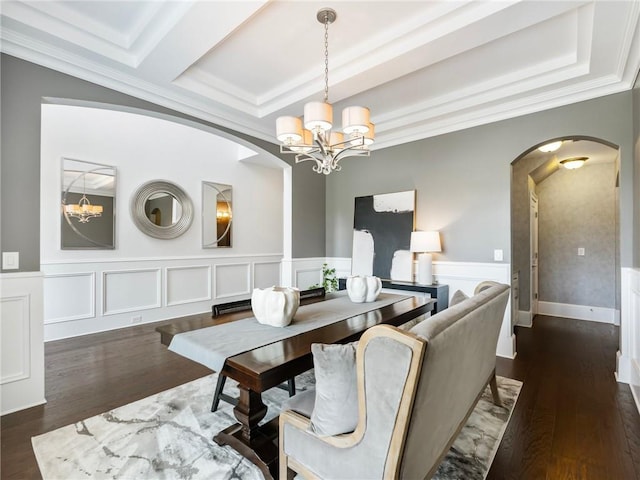 dining room with dark wood-type flooring, ornamental molding, and a chandelier