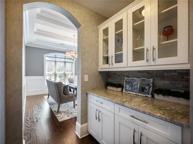 bar with decorative light fixtures, white cabinetry, dark hardwood / wood-style floors, and light stone countertops