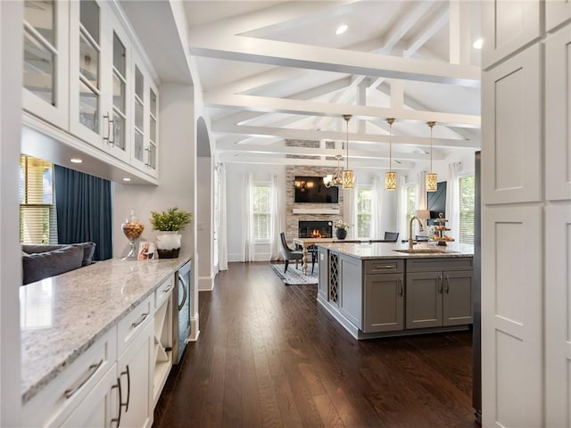 kitchen featuring sink, light stone countertops, lofted ceiling with beams, and white cabinetry