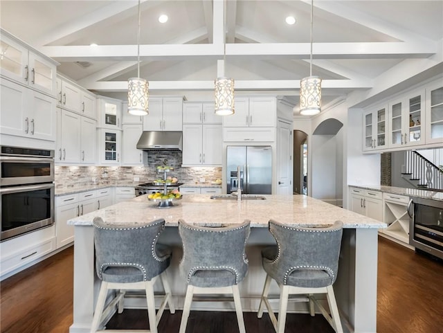 kitchen featuring white cabinetry, lofted ceiling with beams, pendant lighting, and appliances with stainless steel finishes