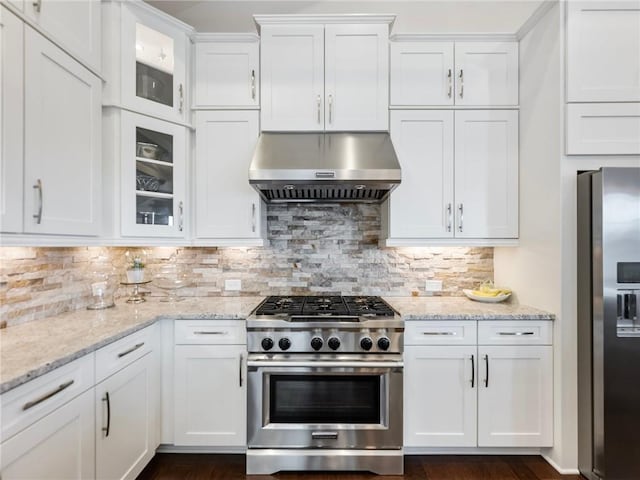 kitchen with appliances with stainless steel finishes, white cabinets, exhaust hood, and decorative backsplash