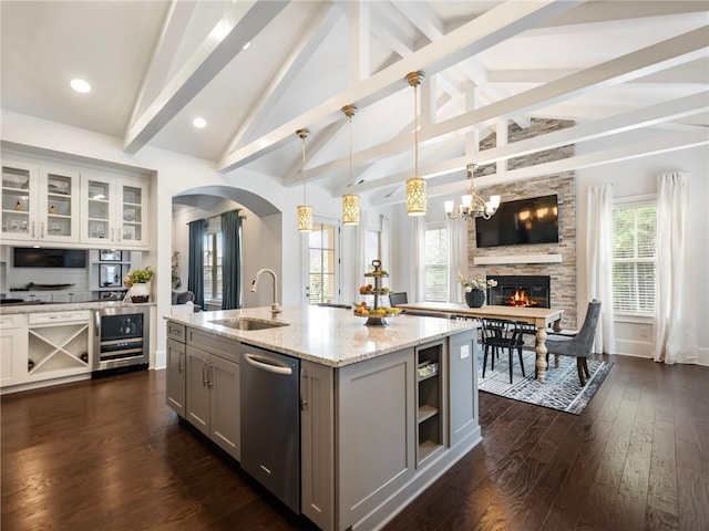 kitchen featuring stainless steel dishwasher, lofted ceiling with beams, hanging light fixtures, gray cabinets, and sink