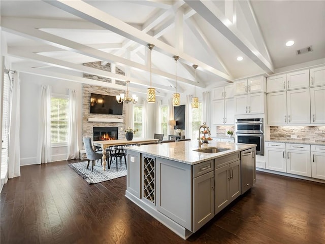 kitchen featuring decorative light fixtures, tasteful backsplash, white cabinetry, double oven, and sink