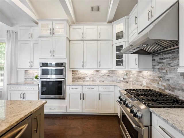 kitchen with light stone counters, appliances with stainless steel finishes, backsplash, and white cabinetry