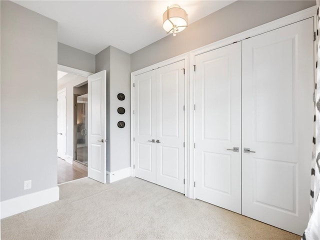 unfurnished bedroom featuring two closets and light carpet