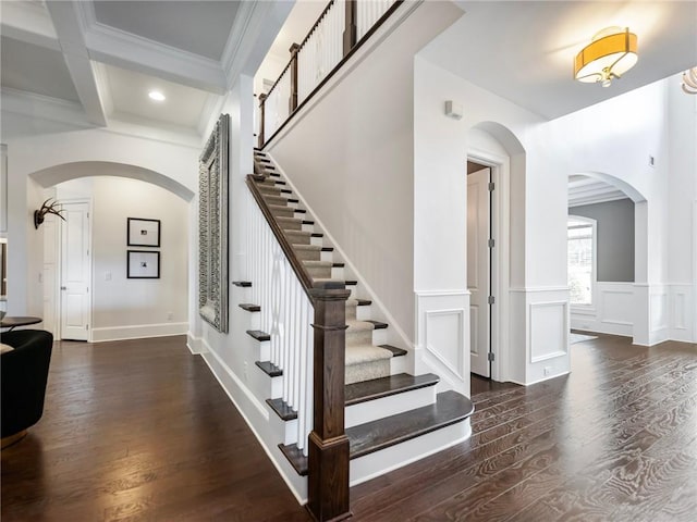 stairway with beamed ceiling, hardwood / wood-style floors, and ornamental molding