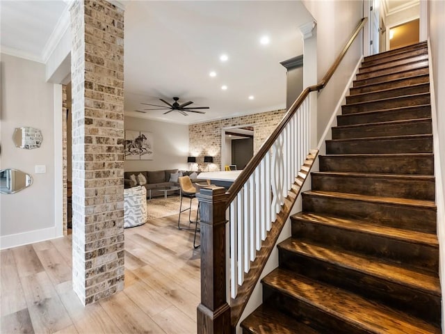 staircase featuring hardwood / wood-style flooring, brick wall, ceiling fan, and crown molding