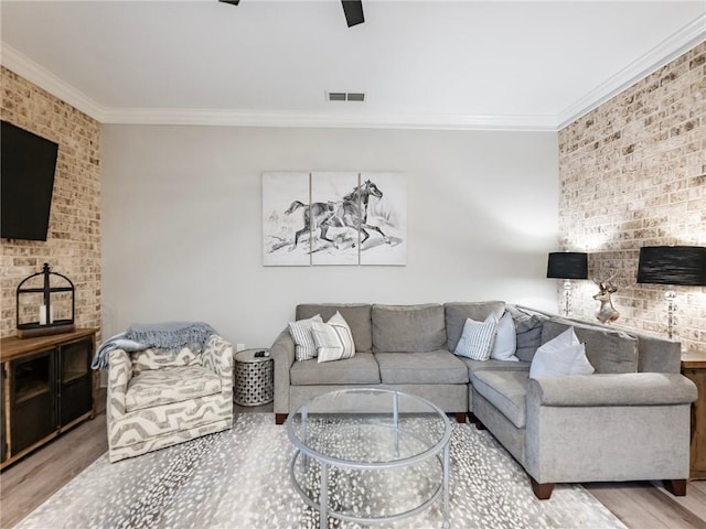 living room with brick wall, ornamental molding, and light hardwood / wood-style floors