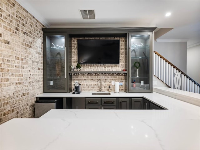 bar with sink, fridge, ornamental molding, and light stone countertops