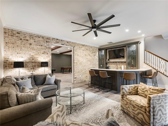 living room with brick wall, ceiling fan, crown molding, and light hardwood / wood-style floors