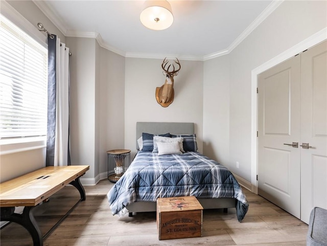 bedroom with light hardwood / wood-style flooring, a closet, and crown molding