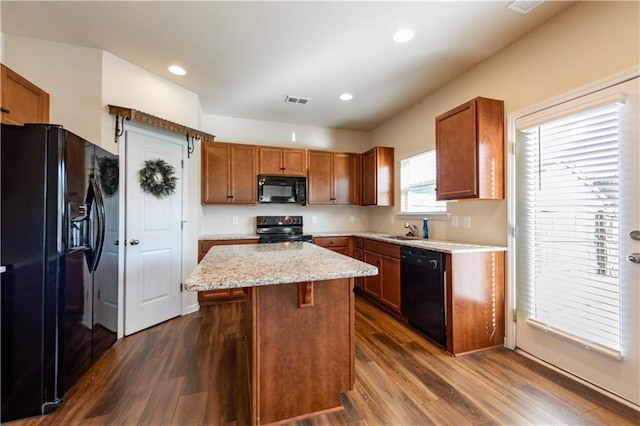 kitchen featuring a center island, black appliances, sink, light stone countertops, and dark hardwood / wood-style flooring