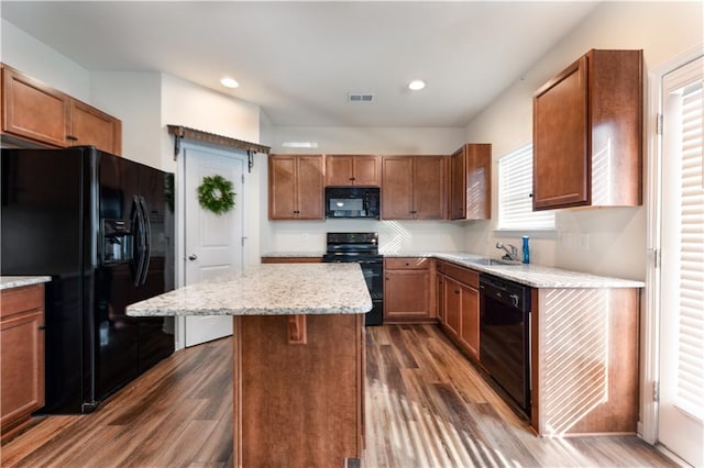 kitchen featuring a center island, black appliances, sink, plenty of natural light, and dark hardwood / wood-style flooring