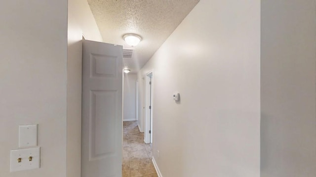 hallway featuring a textured ceiling and baseboards
