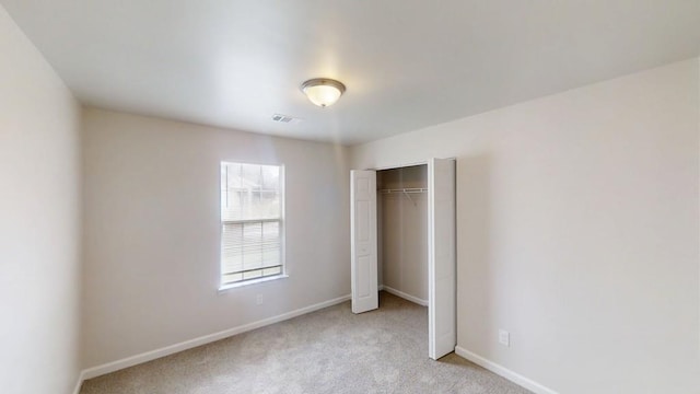 unfurnished bedroom featuring light colored carpet, baseboards, and a closet