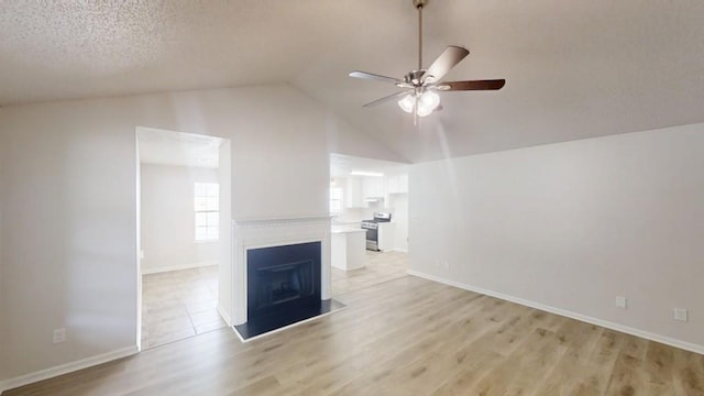 unfurnished living room with a ceiling fan, light wood-style floors, baseboards, a fireplace, and high vaulted ceiling