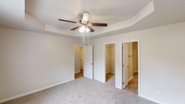 unfurnished bedroom with carpet flooring, a raised ceiling, baseboards, and a textured ceiling