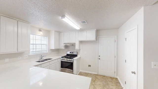 kitchen with gas stove, a sink, under cabinet range hood, white cabinets, and light countertops